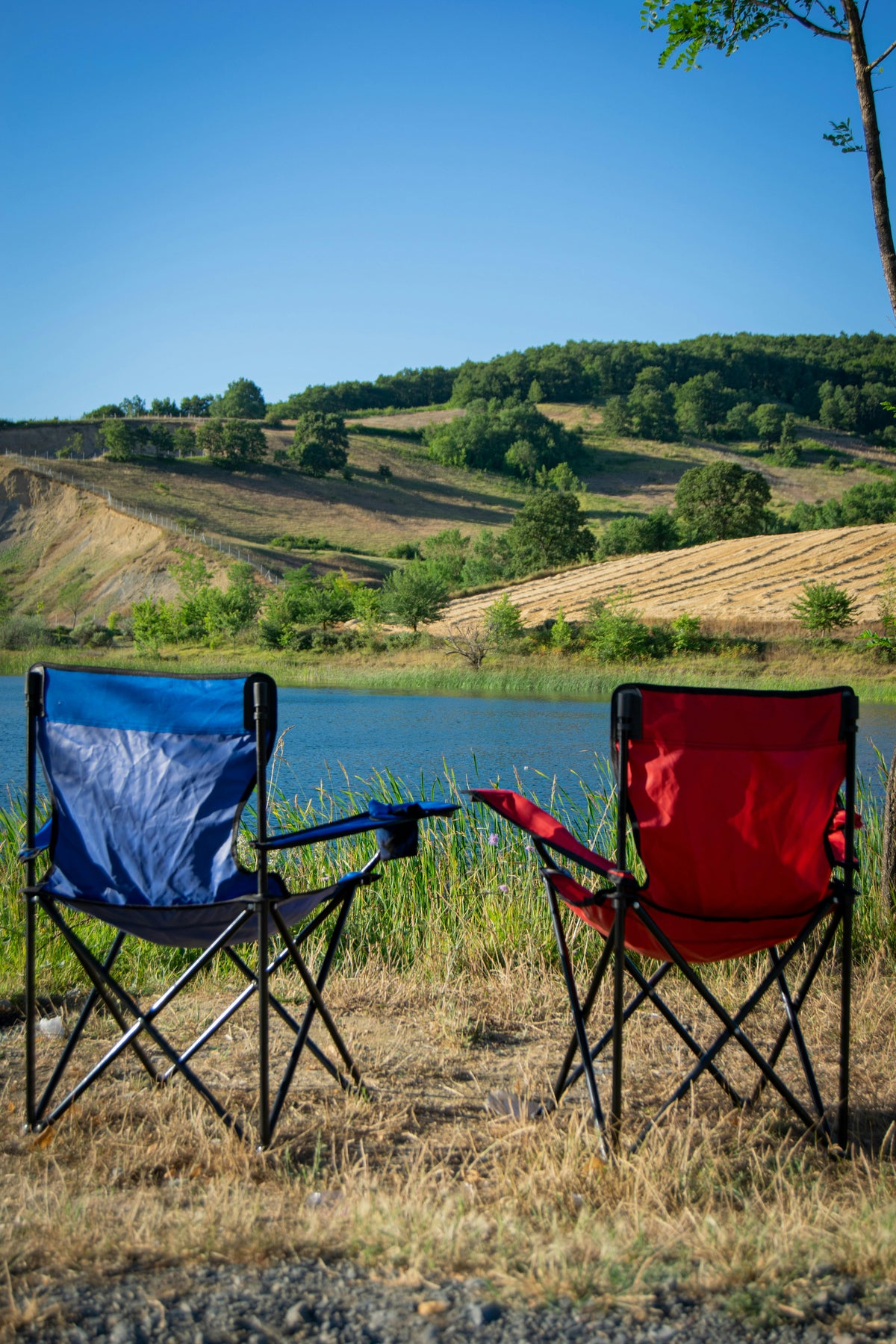 Two folding camping chairs set up by a lake for a relaxing outdoor evening